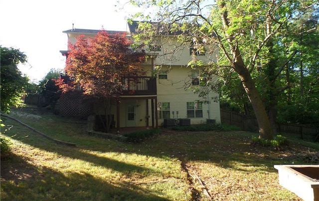 back of house featuring central AC unit, a deck, and a yard