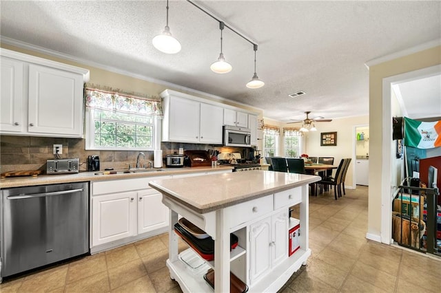 kitchen with stainless steel appliances, white cabinetry, hanging light fixtures, and sink