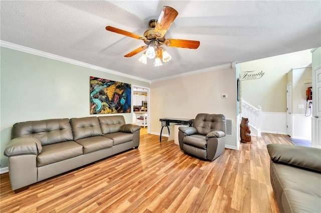 living room featuring a textured ceiling, light hardwood / wood-style floors, ceiling fan, and crown molding