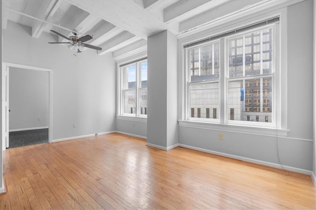 unfurnished room with beamed ceiling, ceiling fan, and light hardwood / wood-style floors