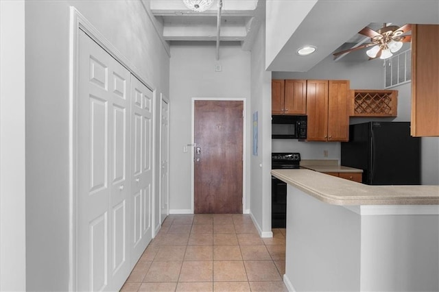 kitchen with light tile patterned floors, kitchen peninsula, ceiling fan, and black appliances