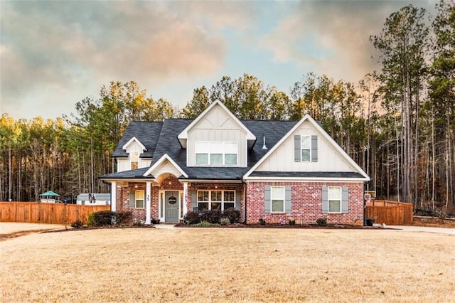 view of front of property featuring brick siding, a front lawn, and fence