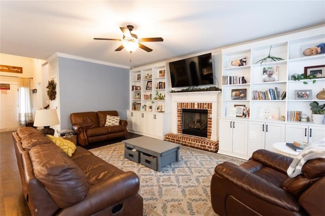 living area with crown molding, wood finished floors, a fireplace, and a ceiling fan