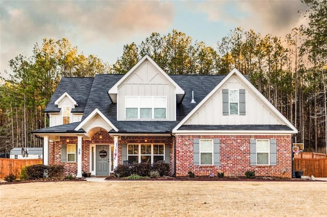 view of front facade featuring fence, a front lawn, board and batten siding, and brick siding