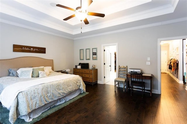 bedroom featuring baseboards, crown molding, a tray ceiling, and wood finished floors