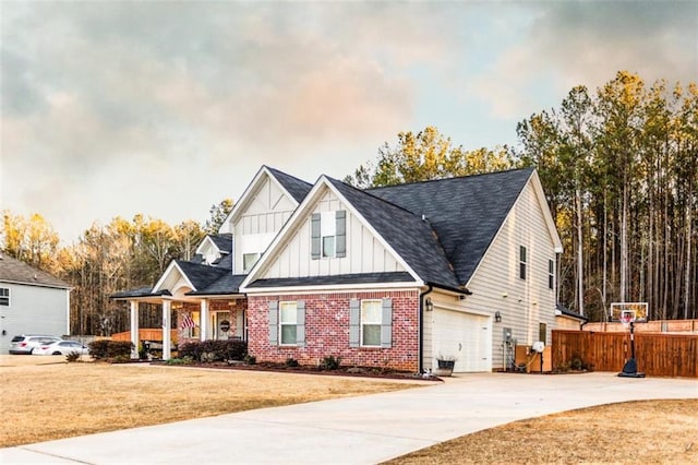 view of front of property with brick siding, board and batten siding, fence, a garage, and a front lawn