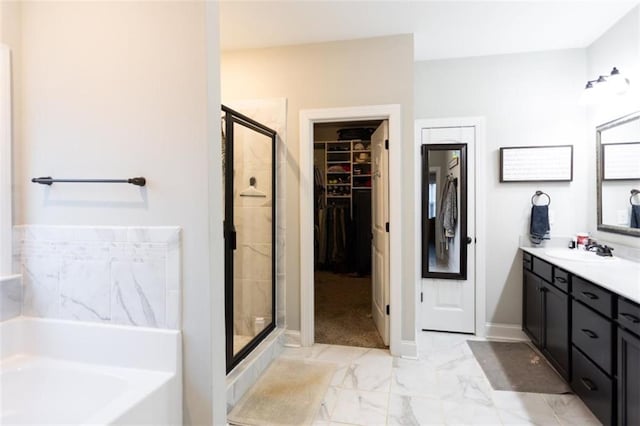 full bathroom with marble finish floor, a garden tub, a spacious closet, a stall shower, and vanity