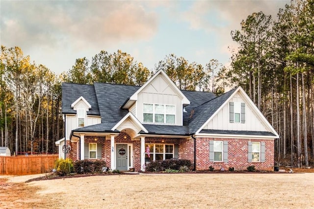 view of front of house featuring brick siding, a front yard, and fence