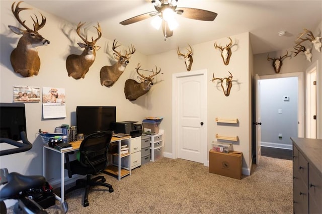 office featuring a ceiling fan, light carpet, and baseboards