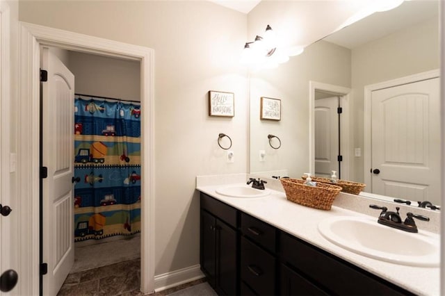 bathroom with double vanity, baseboards, and a sink