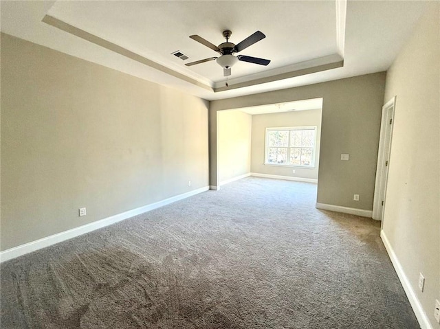 carpeted spare room with ceiling fan and a tray ceiling