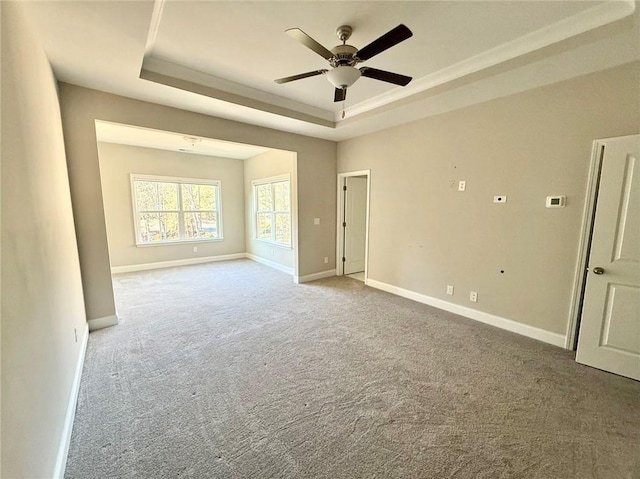 carpeted spare room featuring ceiling fan and a tray ceiling