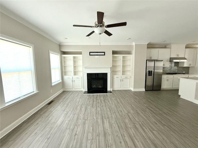 unfurnished living room with ceiling fan, wood-type flooring, and crown molding