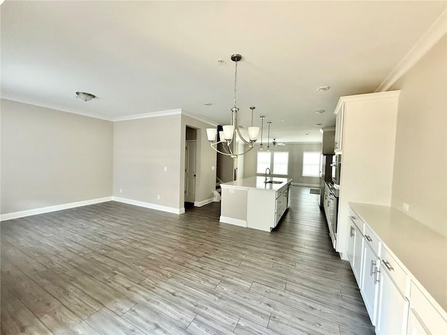 kitchen with hardwood / wood-style flooring, a chandelier, white cabinets, decorative light fixtures, and a center island with sink