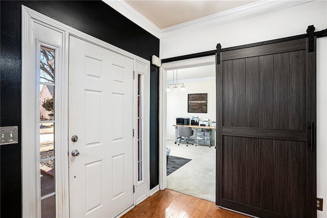 foyer featuring hardwood / wood-style flooring, ornamental molding, and a barn door