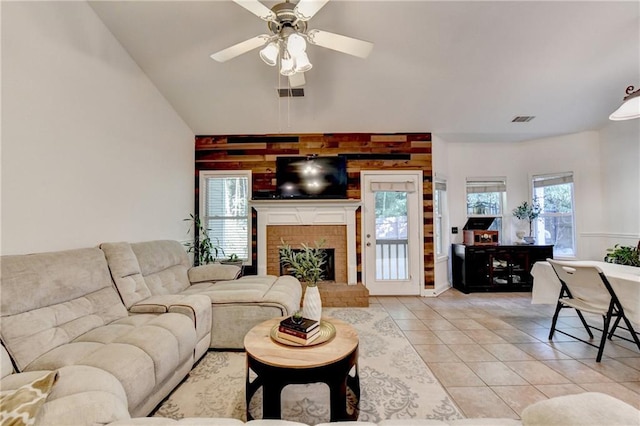 2220 Lily Valley Dr, Lawrenceville, GA 30045 - living room featuring light tile patterned flooring, a ceiling fan, wood walls, a fireplace, and high vaulted ceiling