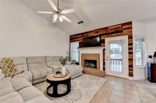 2220 Lily Valley Dr, Lawrenceville, GA 30045 - living room with light tile patterned flooring, a ceiling fan, wooden walls, vaulted ceiling, and a brick fireplace