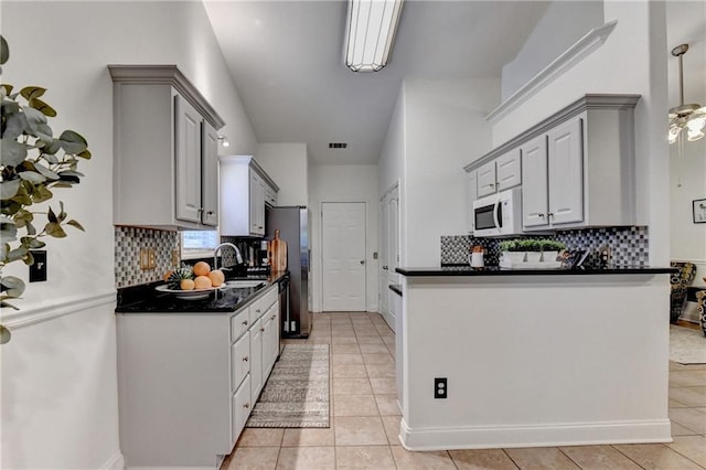 2220 Lily Valley Dr, Lawrenceville, GA 30045 - kitchen with white microwave, dark countertops, gray cabinetry, and backsplash