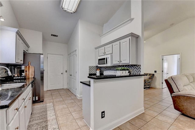 2220 Lily Valley Dr, Lawrenceville, GA 30045 - kitchen featuring white microwave, light tile patterned floors, decorative backsplash, high vaulted ceiling, and open floor plan