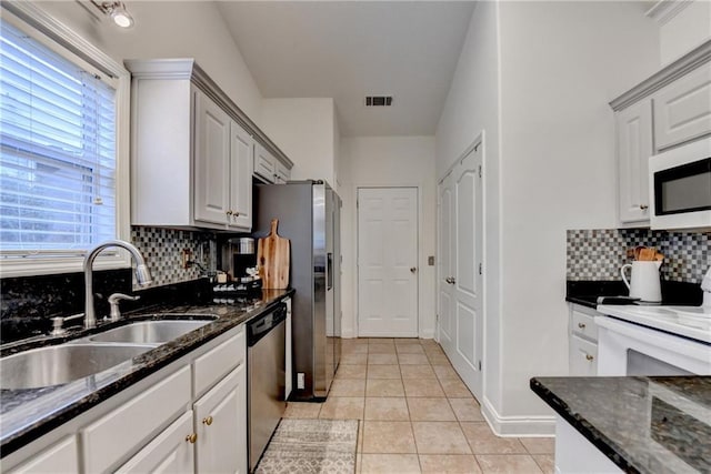 2220 Lily Valley Dr, Lawrenceville, GA 30045 - kitchen with white appliances, decorative backsplash, light tile patterned floors, dark stone counters, and white cabinetry