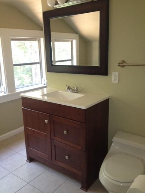 bathroom featuring tile patterned flooring, lofted ceiling, vanity, and toilet