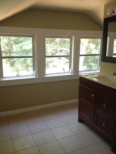 bathroom with vaulted ceiling, tile patterned flooring, and plenty of natural light