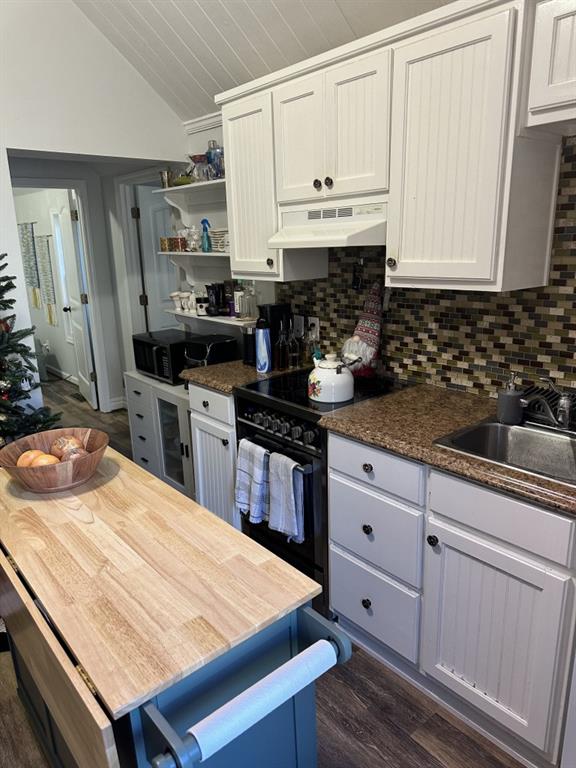 kitchen featuring vaulted ceiling, black appliances, decorative backsplash, and white cabinetry