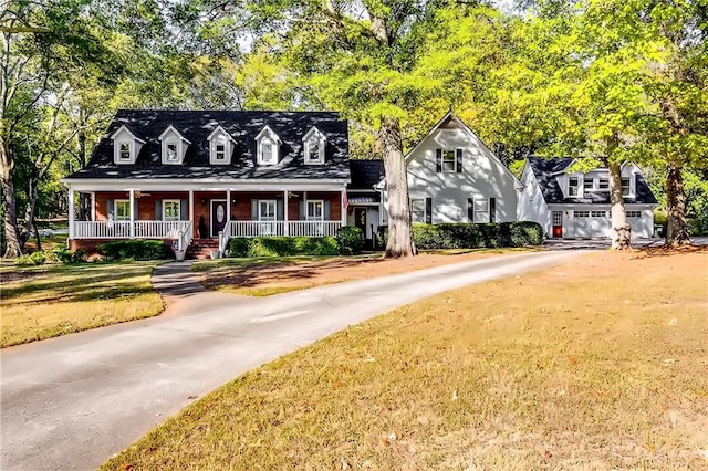 cape cod-style house featuring a porch, a front yard, and a garage