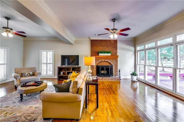 living room featuring ceiling fan, ornamental molding, a fireplace, and hardwood / wood-style floors