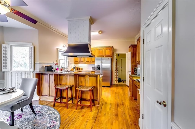 kitchen featuring appliances with stainless steel finishes, light wood-type flooring, backsplash, kitchen peninsula, and a kitchen breakfast bar