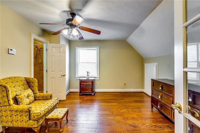 living area featuring a textured ceiling, dark wood-type flooring, vaulted ceiling, and ceiling fan