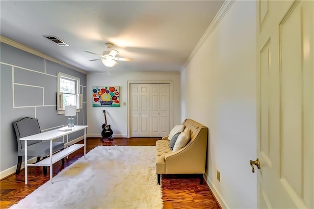 living area featuring dark hardwood / wood-style flooring, ornamental molding, and ceiling fan