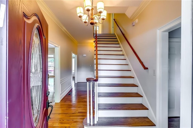 staircase with a notable chandelier, crown molding, and hardwood / wood-style flooring