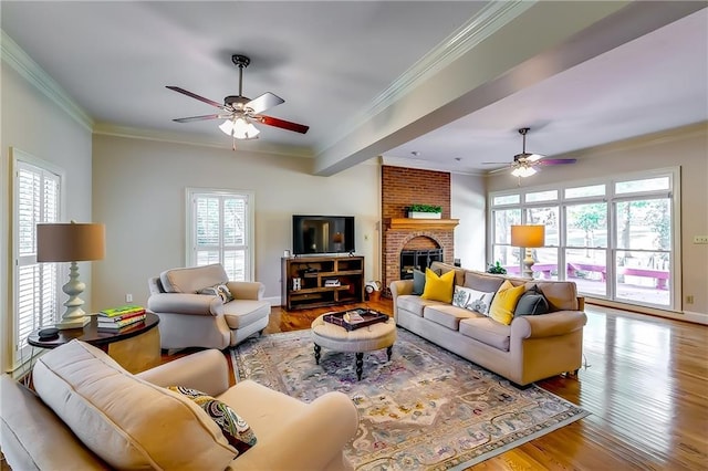 living room featuring crown molding, wood-type flooring, a fireplace, and ceiling fan