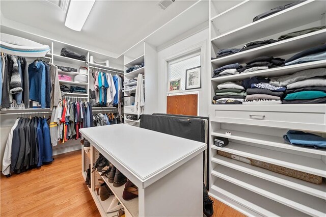 walk in closet with light hardwood / wood-style floors