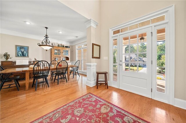 interior space featuring decorative columns, light hardwood / wood-style flooring, and ornamental molding