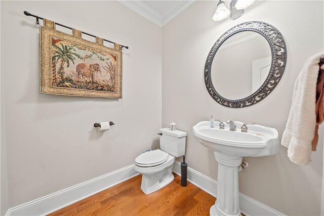 bathroom with hardwood / wood-style flooring, toilet, and crown molding