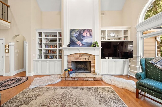 living room with a fireplace, high vaulted ceiling, and light hardwood / wood-style flooring