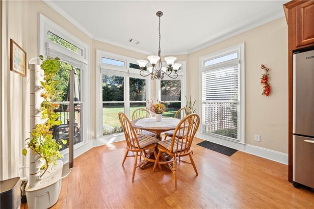 dining area with an inviting chandelier, light hardwood / wood-style floors, and ornamental molding