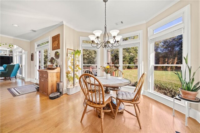 dining area featuring a chandelier, light hardwood / wood-style floors, a wealth of natural light, and crown molding