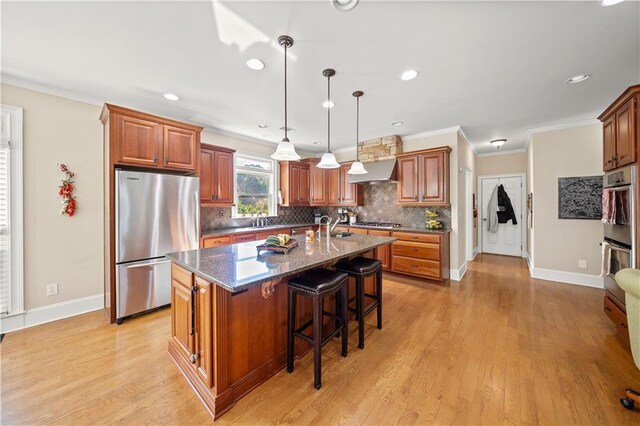 kitchen featuring ventilation hood, light hardwood / wood-style floors, a kitchen island with sink, and appliances with stainless steel finishes