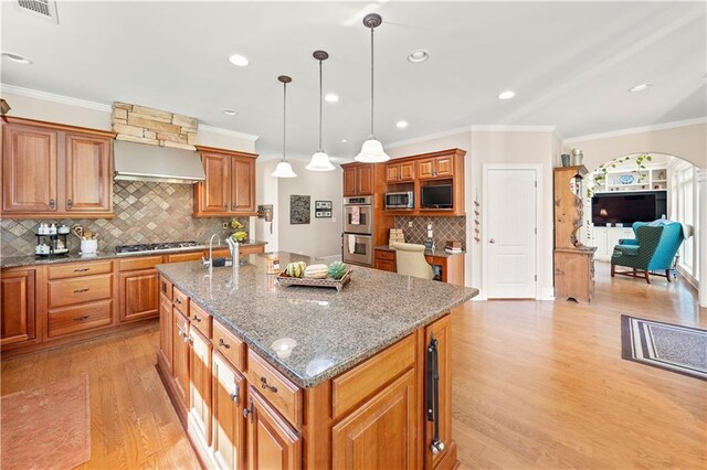 kitchen featuring a center island with sink, pendant lighting, light hardwood / wood-style floors, and stainless steel appliances