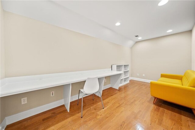 office space with built in desk, light hardwood / wood-style flooring, and lofted ceiling