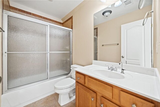 full bathroom with toilet, vanity, tile patterned floors, and bath / shower combo with glass door