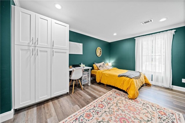 bedroom featuring light wood-type flooring, crown molding, and a closet