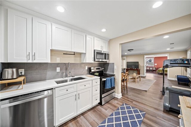 kitchen featuring sink, white cabinetry, stainless steel appliances, and light hardwood / wood-style flooring