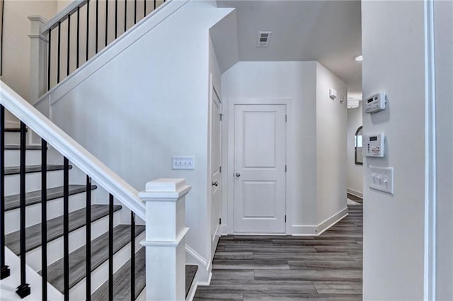 entrance foyer featuring stairs, dark wood-type flooring, visible vents, and baseboards