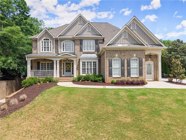 craftsman house with board and batten siding, a porch, brick siding, and a front yard