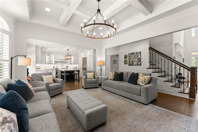 living room with a chandelier, wood finished floors, stairs, coffered ceiling, and beam ceiling