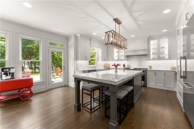 kitchen featuring high quality appliances, plenty of natural light, a center island, a breakfast bar, and recessed lighting